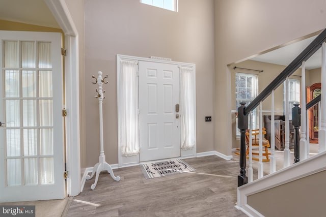 entrance foyer featuring a high ceiling, stairs, baseboards, and wood finished floors