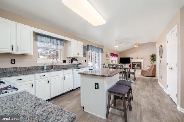 kitchen with a breakfast bar, a center island, white cabinetry, a sink, and dishwasher