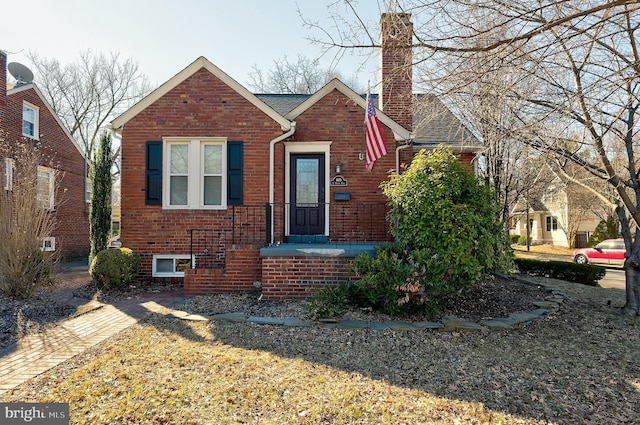 view of front of house with roof with shingles, a chimney, and brick siding