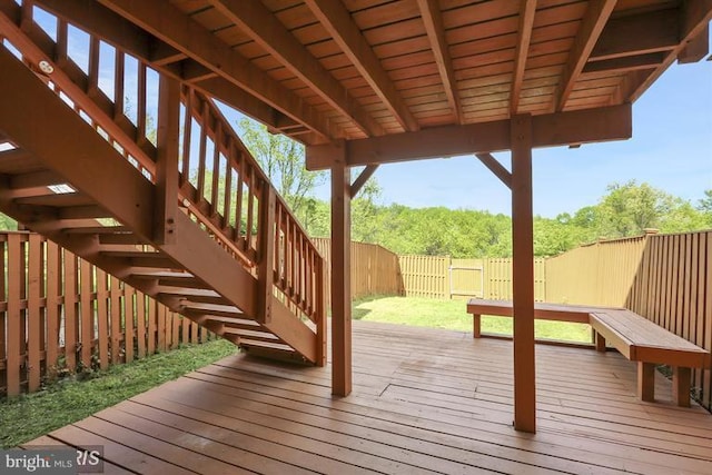 wooden terrace featuring stairs, a lawn, and a fenced backyard