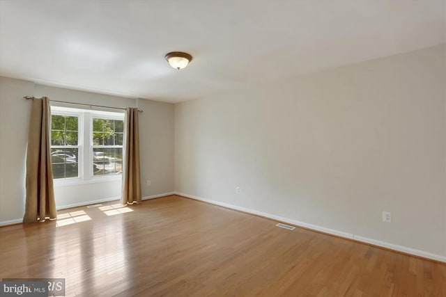 spare room featuring visible vents, baseboards, and wood finished floors