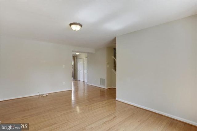 empty room featuring visible vents, baseboards, and wood finished floors