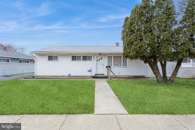 single story home with a shingled roof, fence, and a front lawn