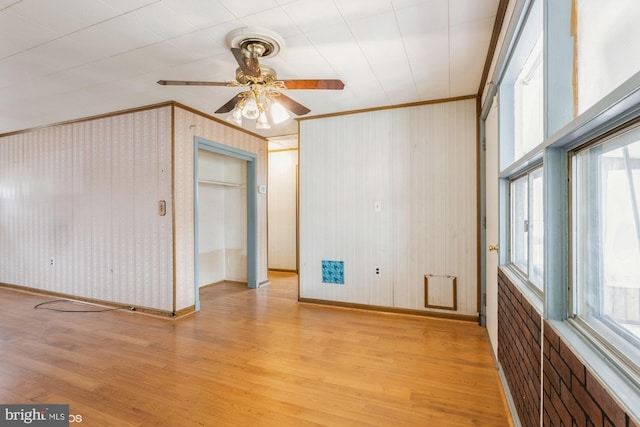 spare room featuring ornamental molding, light wood-style floors, and a healthy amount of sunlight