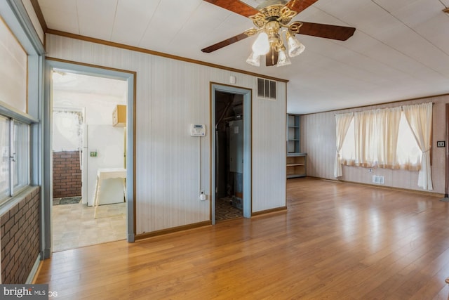 interior space featuring visible vents, baseboards, a ceiling fan, hardwood / wood-style flooring, and crown molding