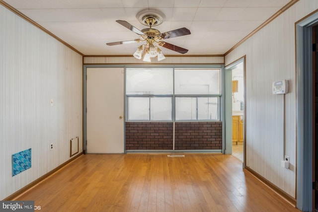 empty room with light wood-style floors, crown molding, baseboards, and a ceiling fan