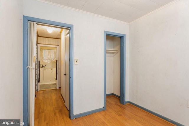 unfurnished bedroom with ornamental molding, a closet, light wood-style flooring, and baseboards