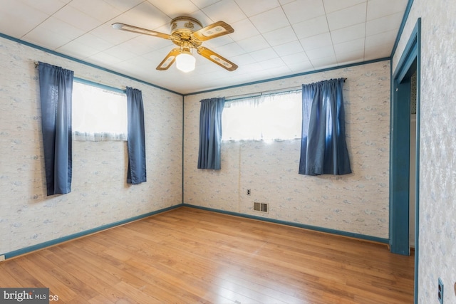 spare room with visible vents, ceiling fan, baseboards, and wood finished floors