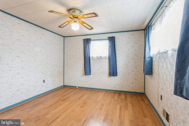 spare room featuring a ceiling fan, baseboards, visible vents, and wood finished floors