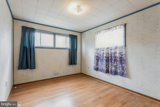 spare room featuring baseboards, visible vents, and hardwood / wood-style floors