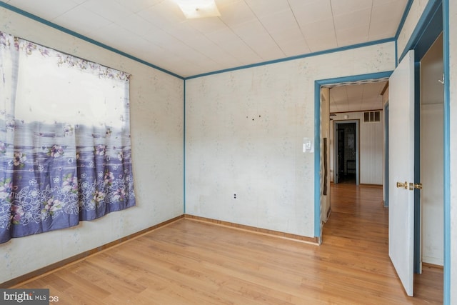 unfurnished room featuring baseboards, visible vents, and wood finished floors