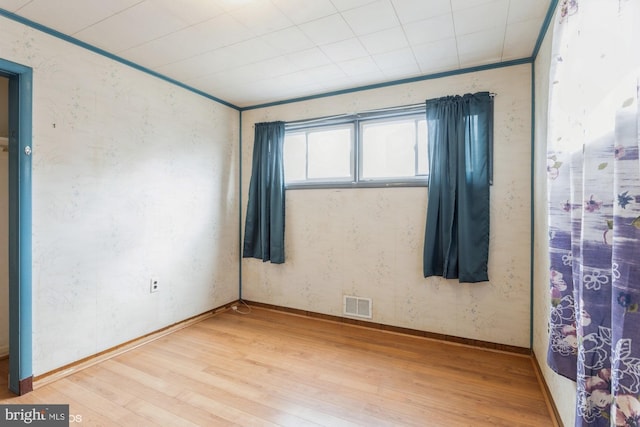 empty room featuring light wood-style floors, baseboards, and visible vents