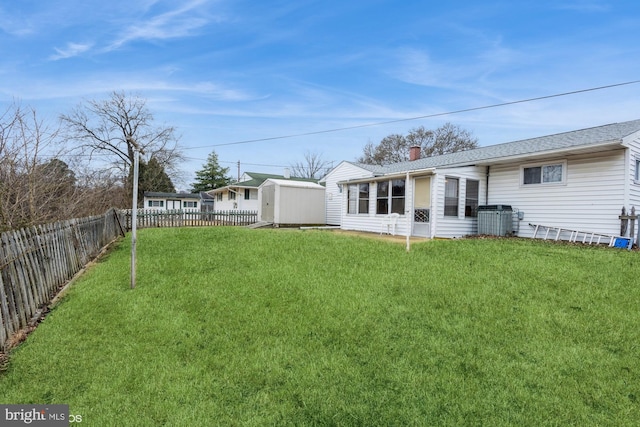 back of house featuring an outbuilding, central AC, a lawn, and a fenced backyard