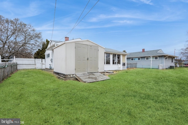 rear view of property with a fenced backyard, an outbuilding, and a yard