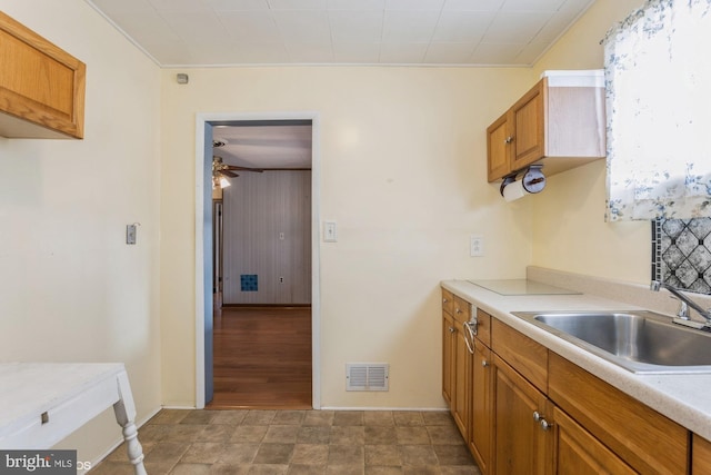 kitchen with brown cabinetry, visible vents, and a sink