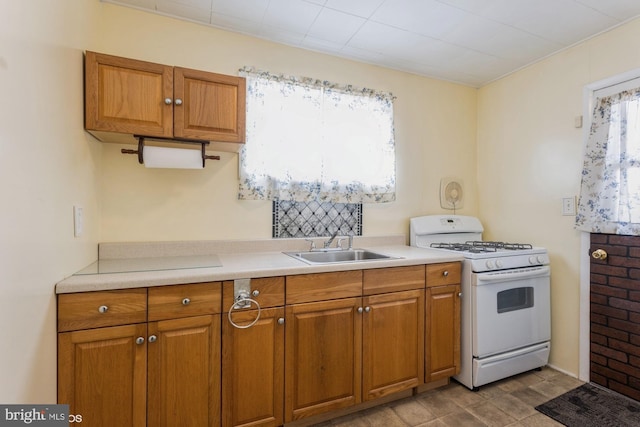 kitchen with brown cabinets, a sink, and white gas stove