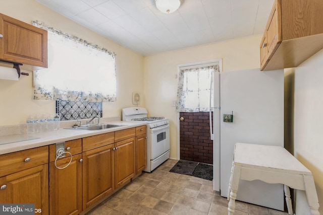 kitchen with brown cabinetry, white appliances, light countertops, and a sink