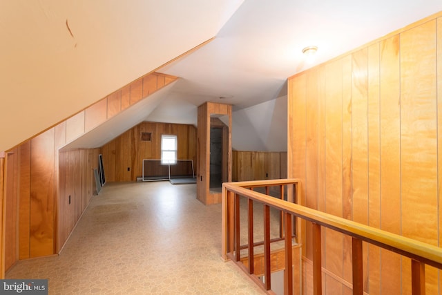 bonus room featuring lofted ceiling, wood walls, and light floors