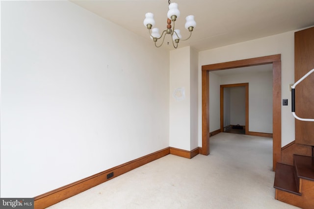 empty room with a notable chandelier, baseboards, and carpet flooring