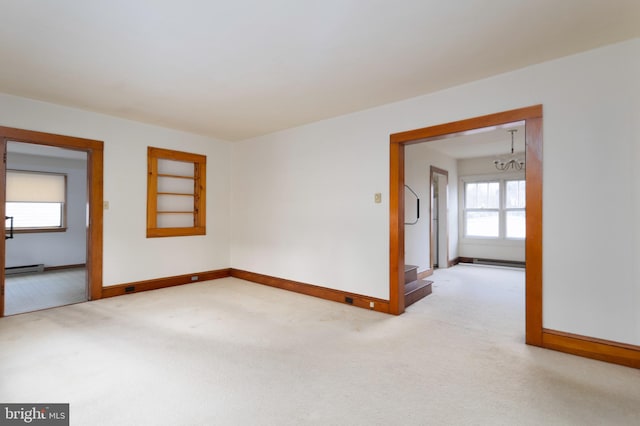 carpeted spare room with a baseboard radiator, baseboards, and a chandelier