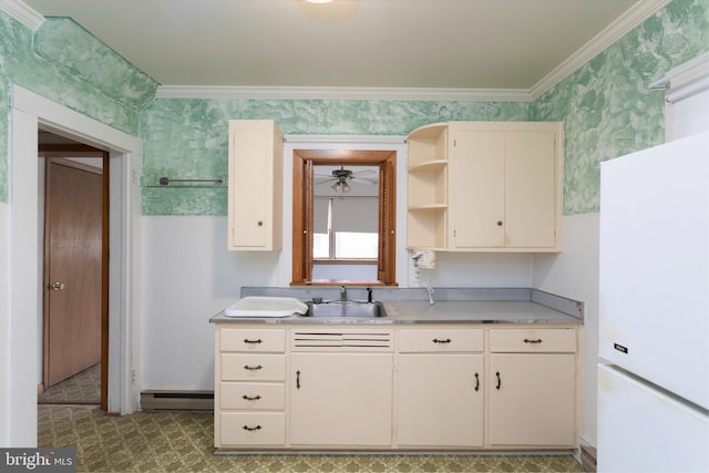 kitchen with a sink, light countertops, baseboard heating, freestanding refrigerator, and wallpapered walls