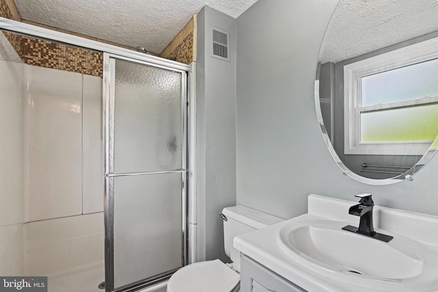 bathroom featuring visible vents, toilet, a textured ceiling, vanity, and a shower stall