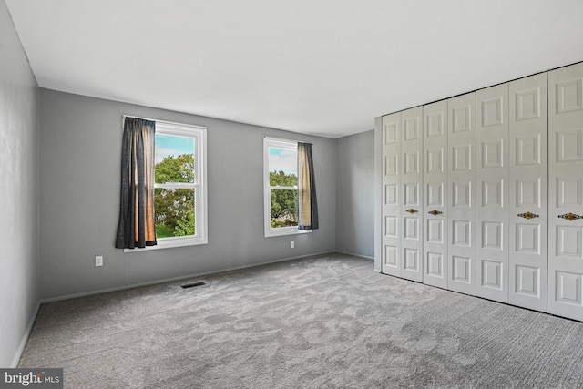 unfurnished bedroom with baseboards, carpet, visible vents, and a closet