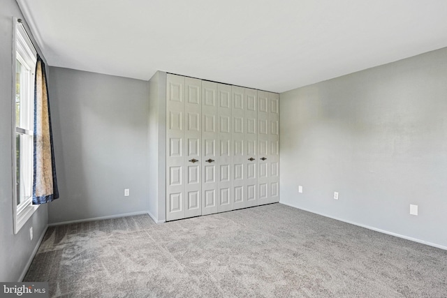 unfurnished bedroom featuring carpet floors, baseboards, and a closet