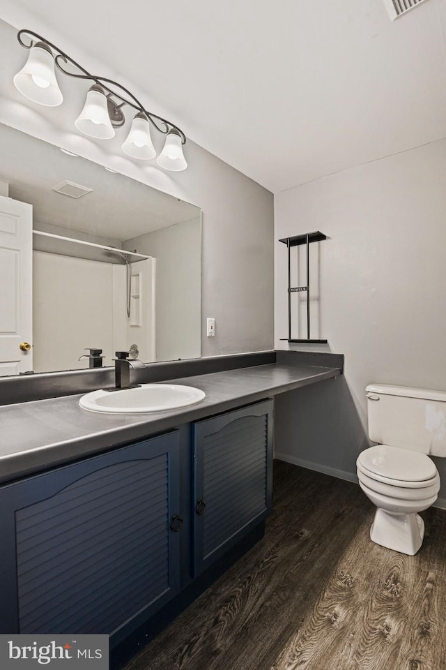 bathroom featuring toilet, wood finished floors, visible vents, vanity, and baseboards