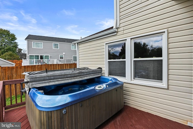 deck with a hot tub and fence