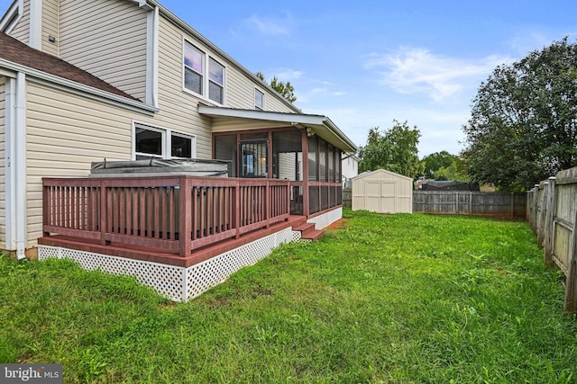 view of yard featuring a deck, a fenced backyard, an outdoor structure, a sunroom, and a shed