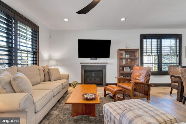 living room featuring a glass covered fireplace, a healthy amount of sunlight, recessed lighting, and wood finished floors