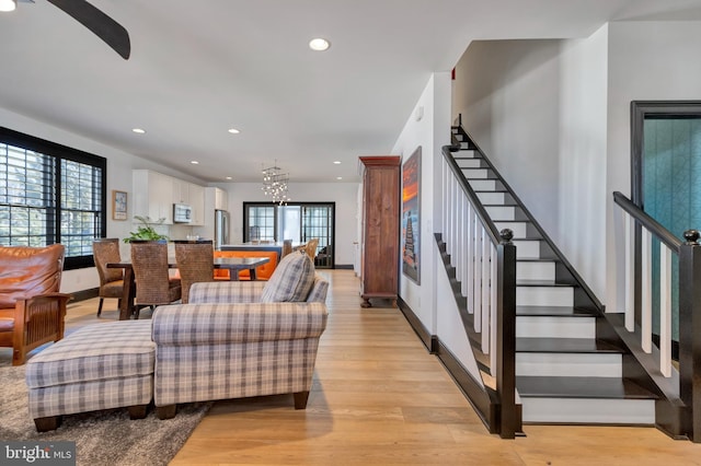 living room featuring light wood finished floors, recessed lighting, a chandelier, baseboards, and stairs