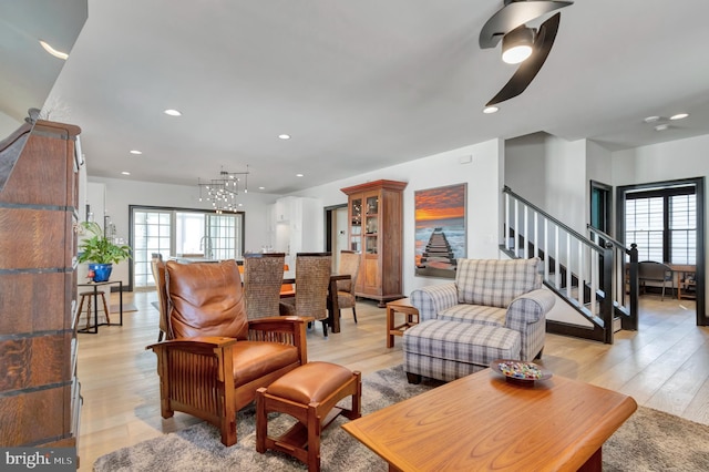 living room featuring light wood-type flooring, recessed lighting, and stairs