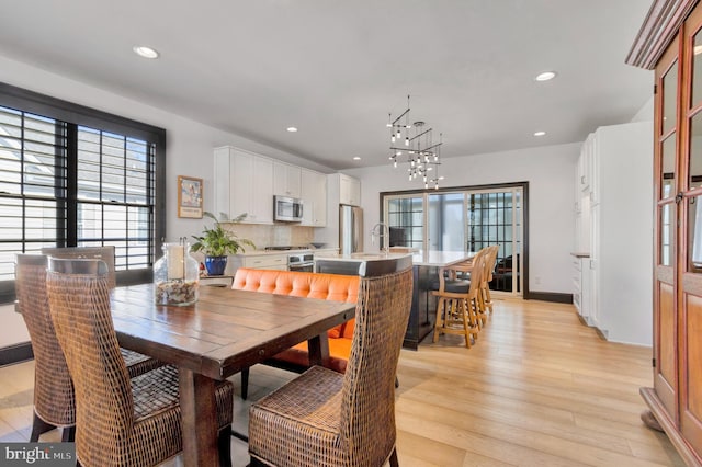 dining room with a chandelier, a healthy amount of sunlight, recessed lighting, and light wood-style floors