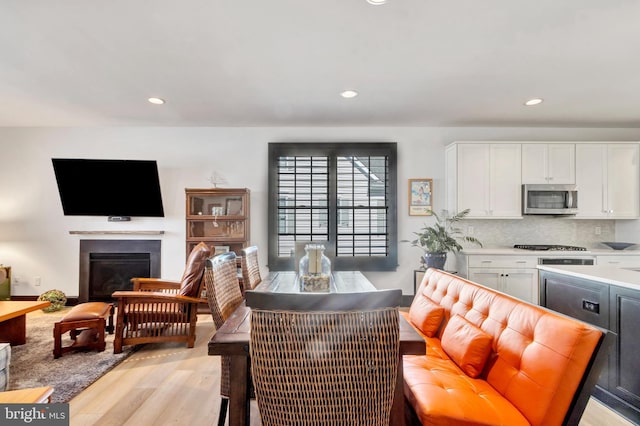 dining area featuring light wood-type flooring, a glass covered fireplace, and recessed lighting