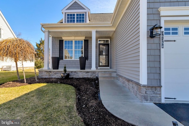 doorway to property featuring a garage, a porch, and a yard