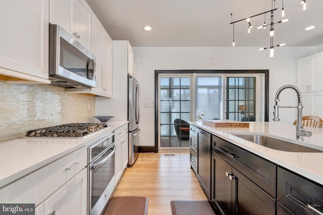 kitchen with appliances with stainless steel finishes, light countertops, white cabinetry, and a sink