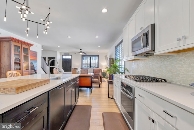 kitchen featuring appliances with stainless steel finishes, light countertops, a sink, and white cabinetry