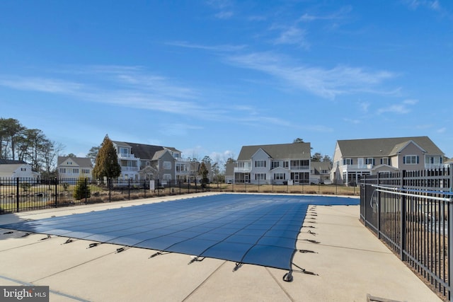 community pool featuring a residential view, fence, and a patio