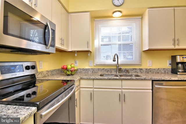 kitchen featuring stainless steel appliances, a sink, and light stone countertops