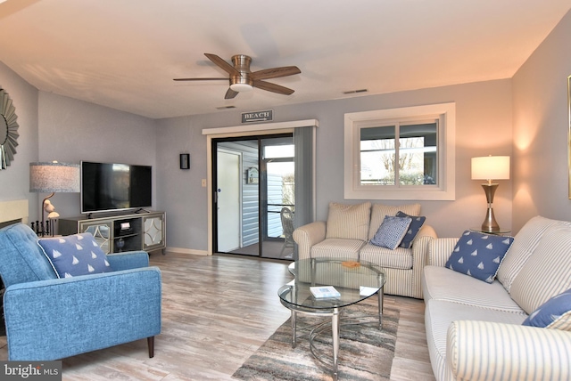 living room featuring a ceiling fan, baseboards, visible vents, and wood finished floors