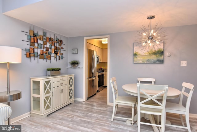 dining room with light wood-style flooring, a chandelier, and baseboards