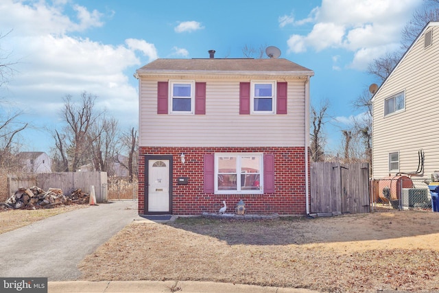 traditional home with fence, aphalt driveway, and brick siding