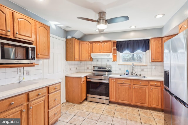 kitchen featuring light tile patterned floors, stainless steel appliances, light countertops, under cabinet range hood, and a sink