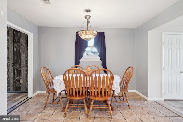 dining space featuring light tile patterned floors, visible vents, and baseboards