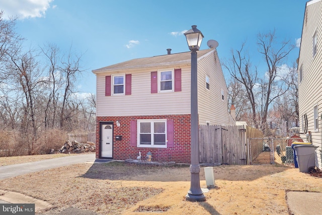 view of front of home with brick siding and fence