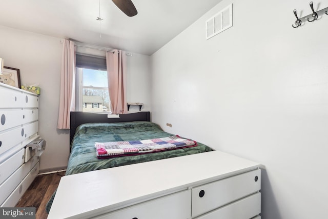 bedroom with dark wood-style floors, visible vents, and a ceiling fan