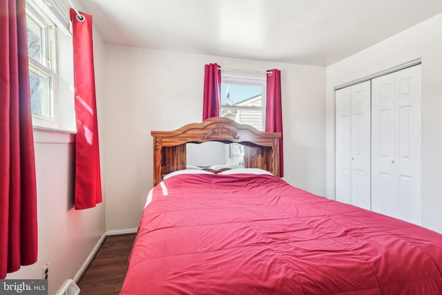 bedroom with a closet, visible vents, baseboards, and wood finished floors