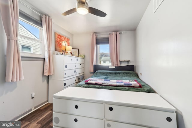 bedroom with dark wood-style floors, visible vents, baseboards, and a ceiling fan